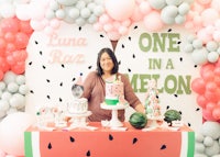 a woman standing in front of a table with balloons and watermelon